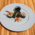 Plato de sushi con rollos de alga nori, camarones y salsa de soja en un fondo de madera.